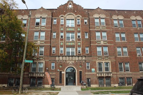 A large red brick building with a black car parked in front.