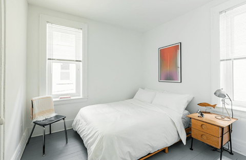 A bedroom with a bed, chair, and table.