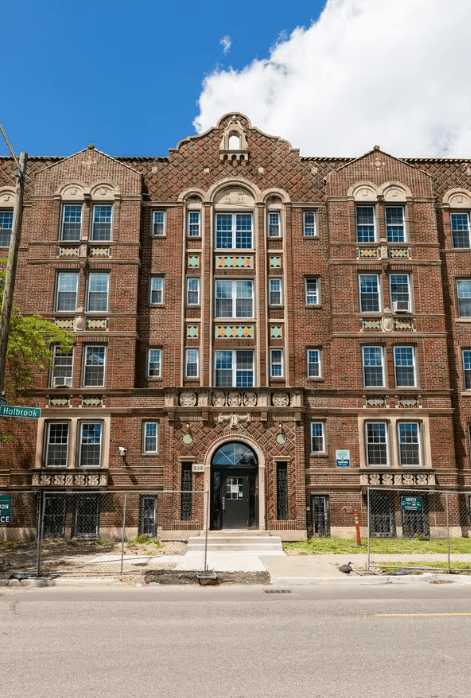 A large red brick building with a black gate in front.