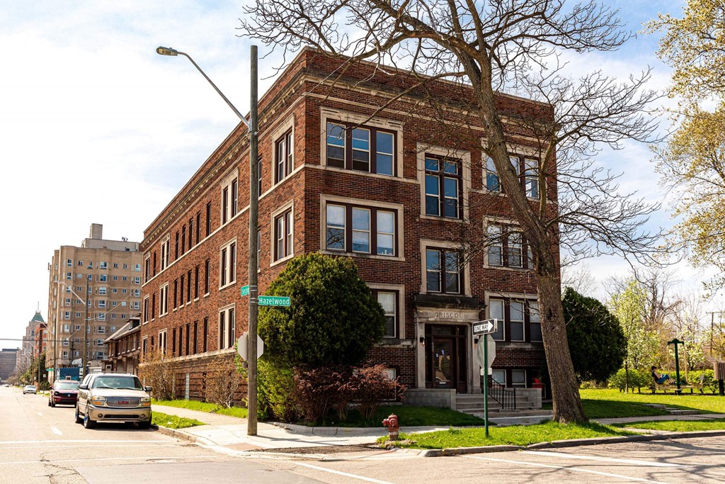 A large red brick building with a tree in front of it.