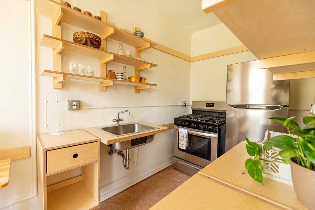 A kitchen with wooden shelves and a stainless steel oven.