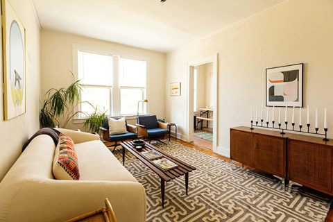 A living room with a sofa, chairs, and a rug.