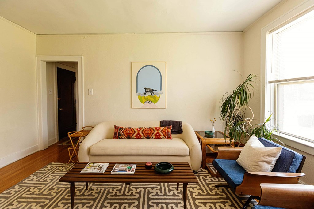 A living room with a white couch and a painting on the wall.