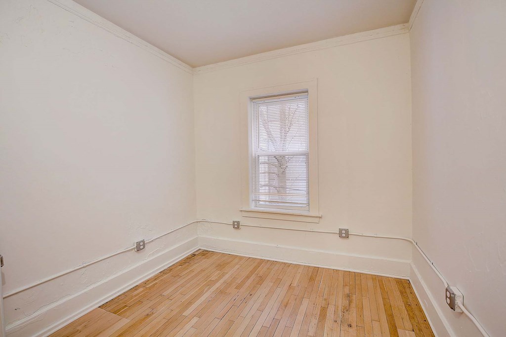 A room with a window and wooden flooring.