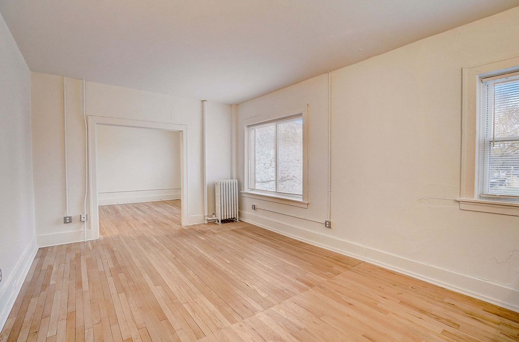 A room with wooden flooring and a window with blinds.