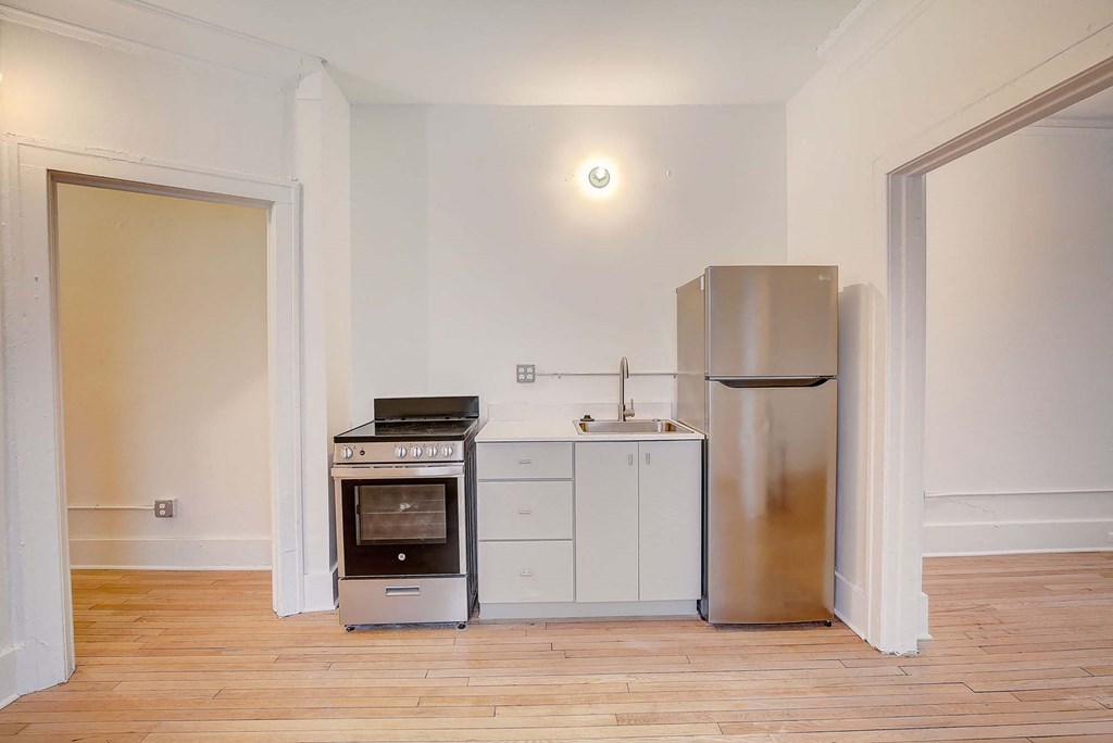 A kitchen with a stove, sink, and fridge.
