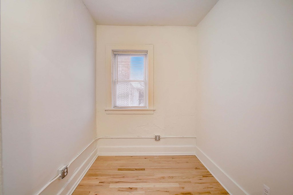 A room with a window and wooden flooring.