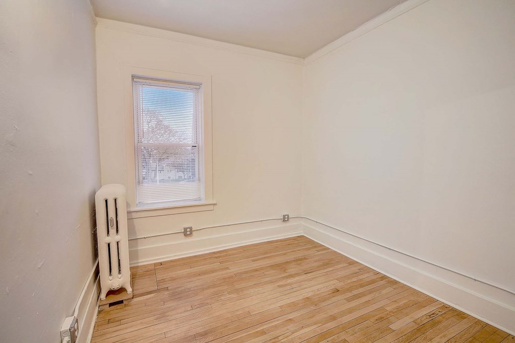A room with a window and a radiator on the floor.