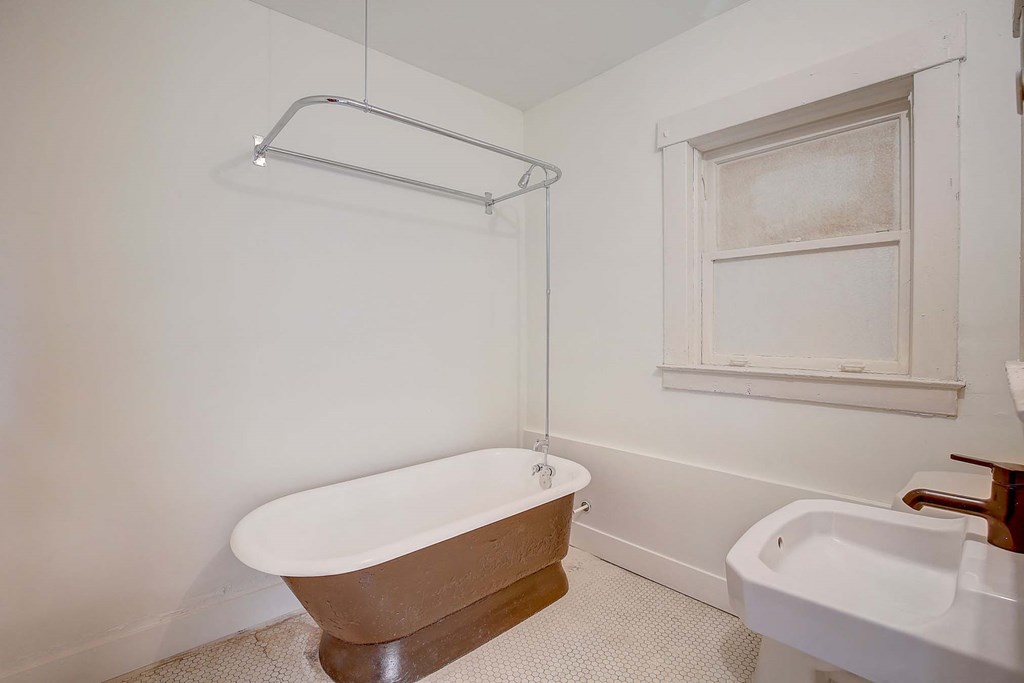 A white bathroom with a claw foot tub and a white sink.