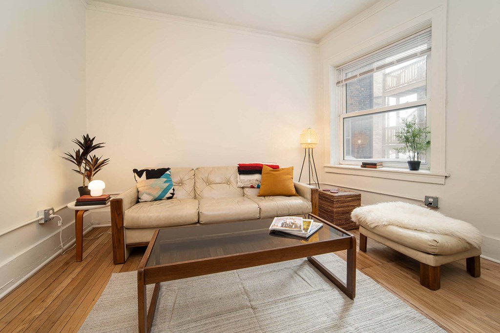 A living room with a white couch, a wooden coffee table, and a window.