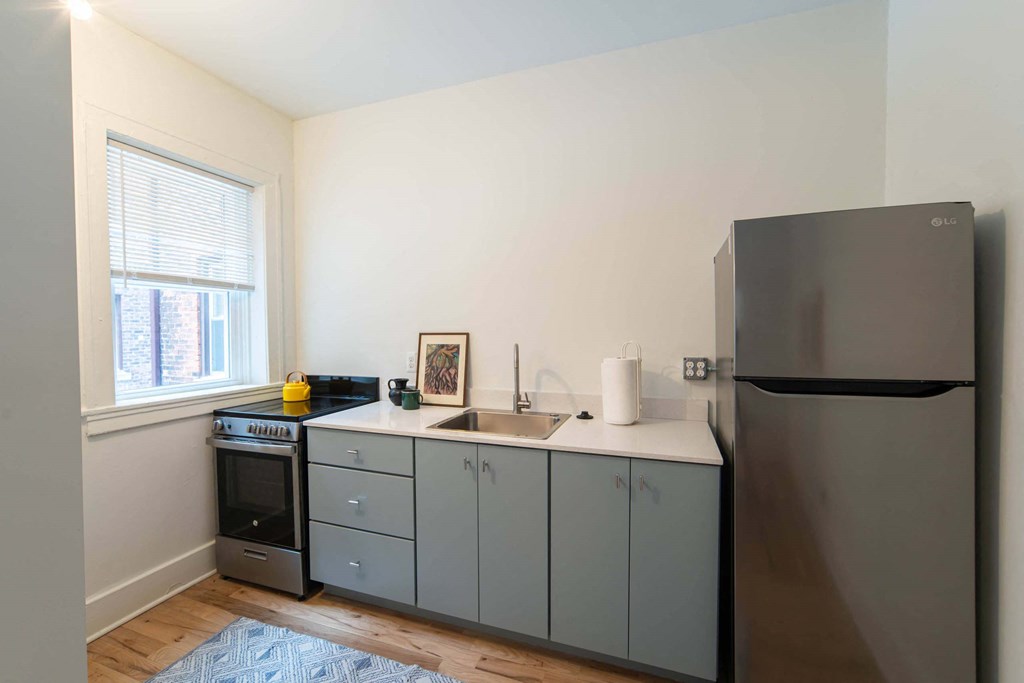 A kitchen with a refrigerator, sink, and cabinets.