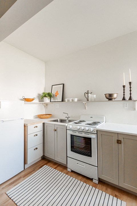 A white kitchen with a stove top oven and a white fridge.