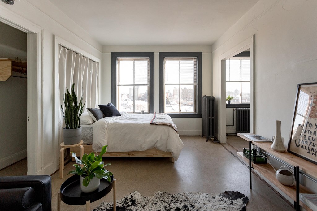 A bedroom with a bed, a chair, a table, and a window.