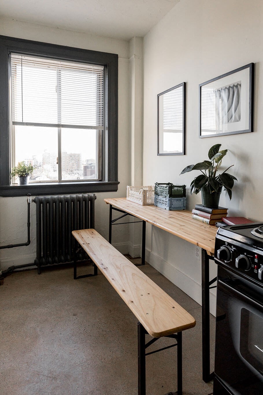 A black stove sits in a kitchen with a window and two potted plants.