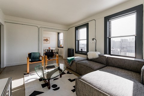 A living room with a grey couch and a glass table.