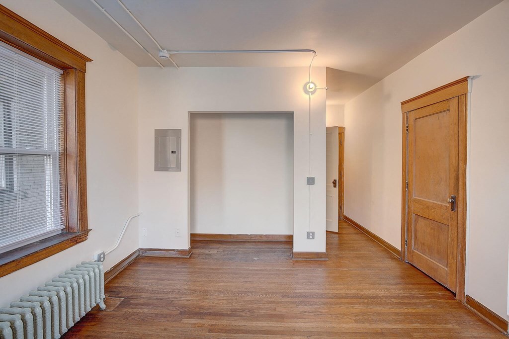 A room with wooden floors and a window with blinds.
