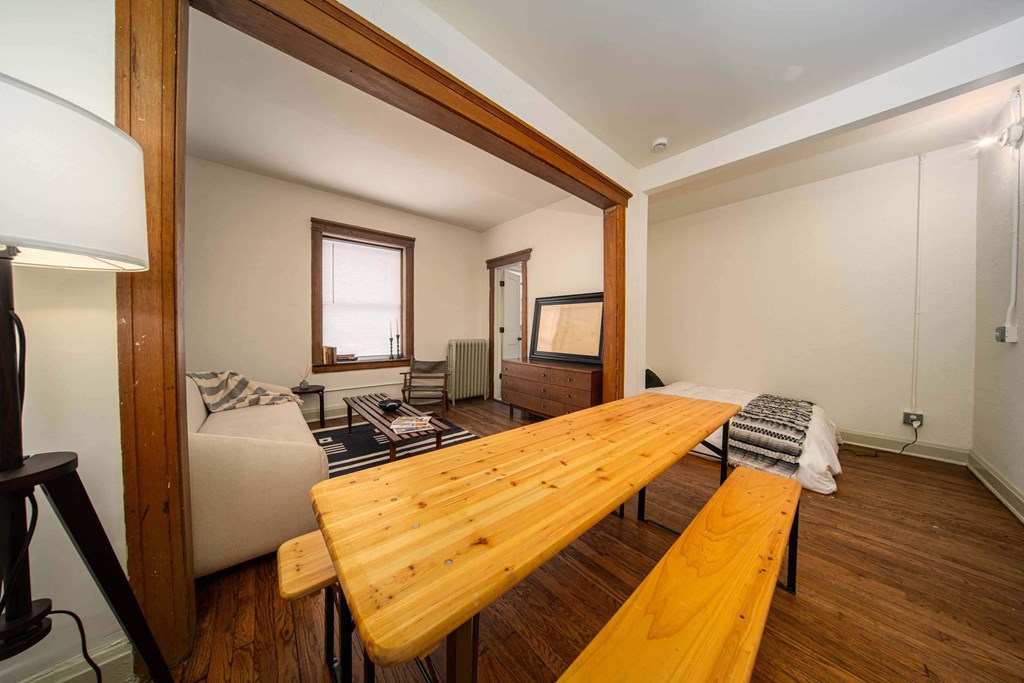 A wooden table and bench are in a room with a couch and a window.