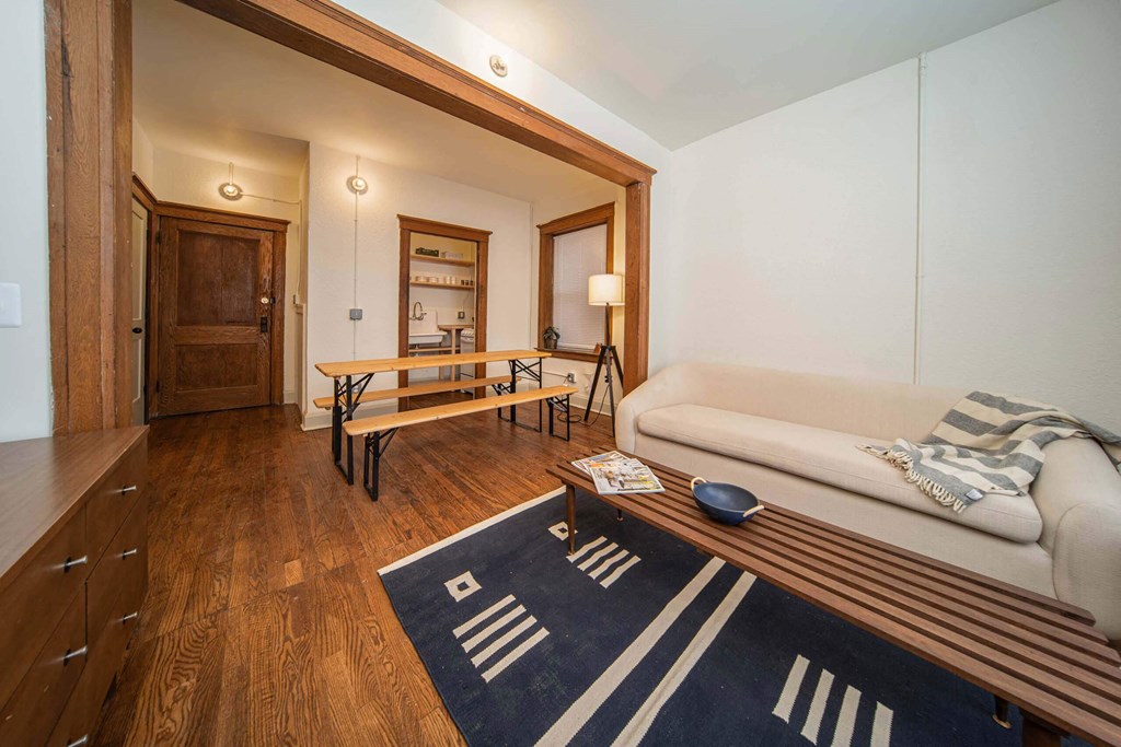 A living room with a couch, a coffee table, and a rug with a pattern.
