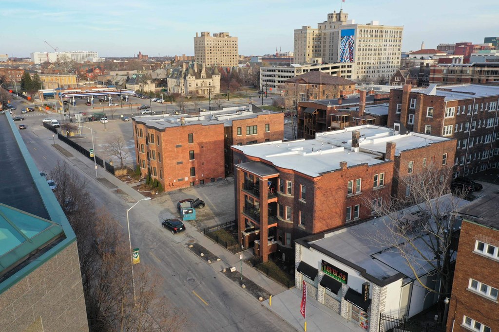 A city street with buildings on either side and cars parked on the side of the road.