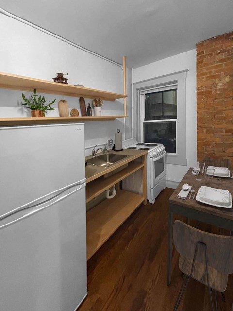 A kitchen with a white refrigerator, wooden shelves, and a brown table.