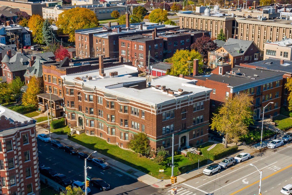 A large red brick building with a green roof sits in the middle of a city street.