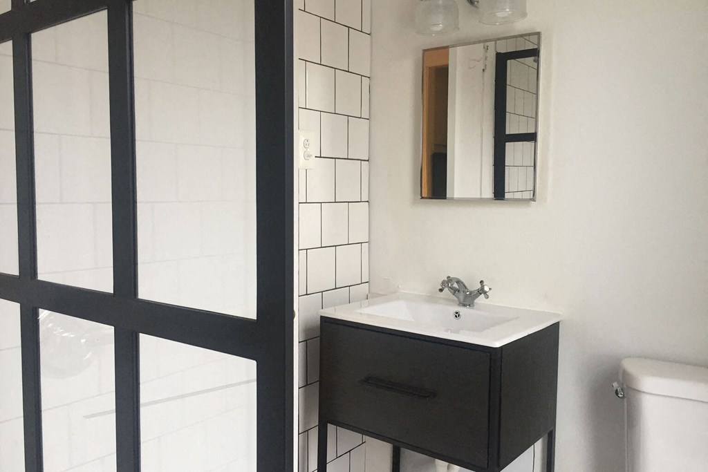 A white sink with a black drawer and a mirror above it.