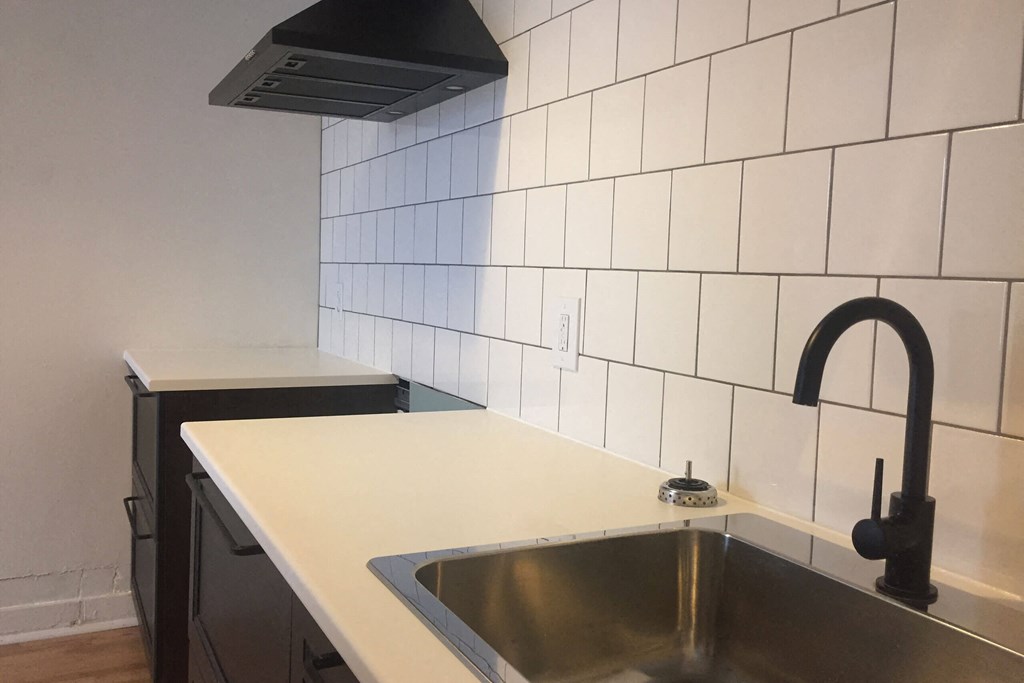 A kitchen with a sink and a black faucet.