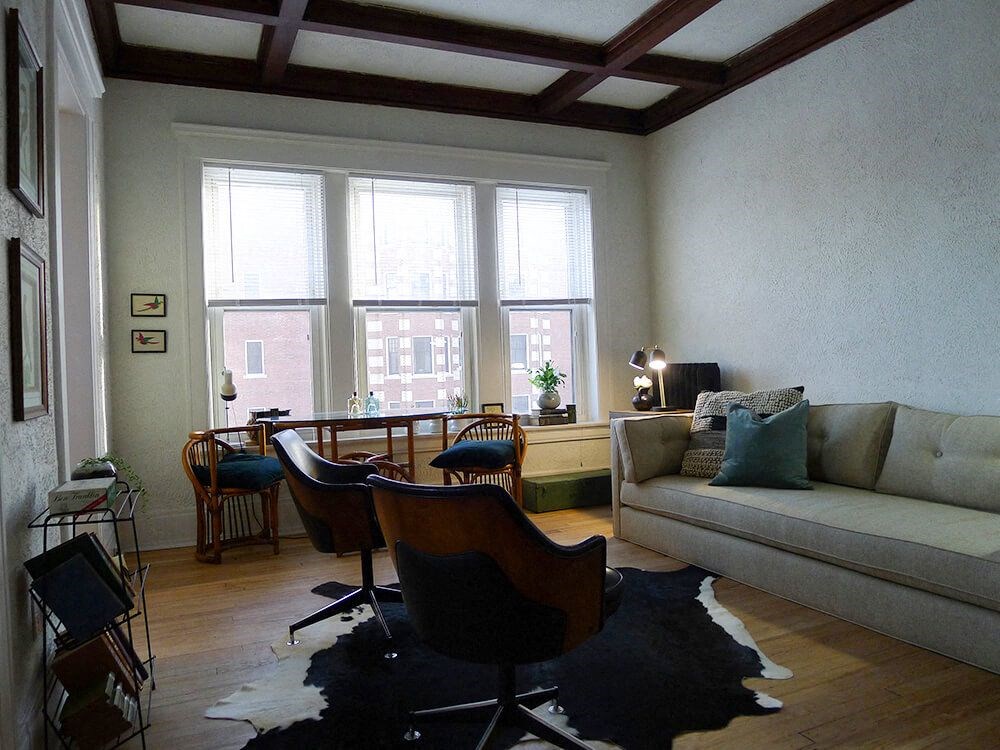 A living room with a couch, chairs, and a rug.