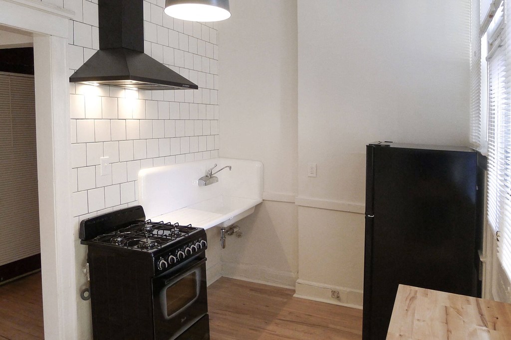 A black stove is in a kitchen with white tiles.