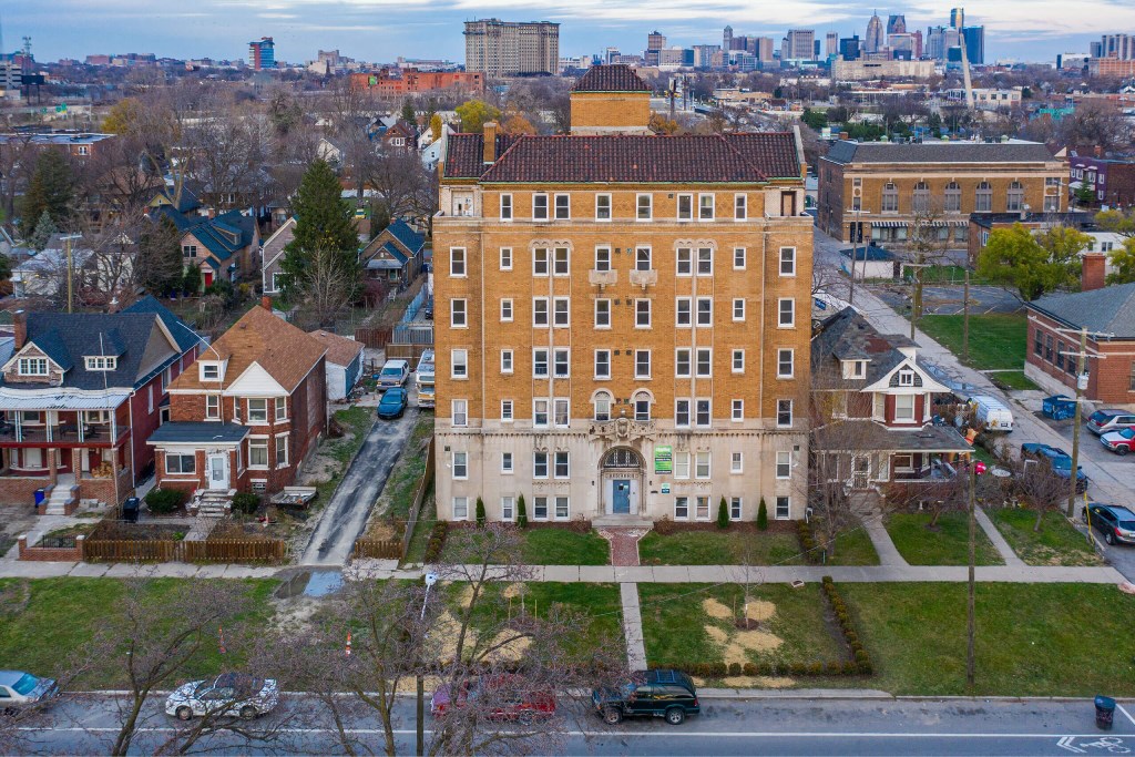 A large building with a red roof is in the middle of a residential area.