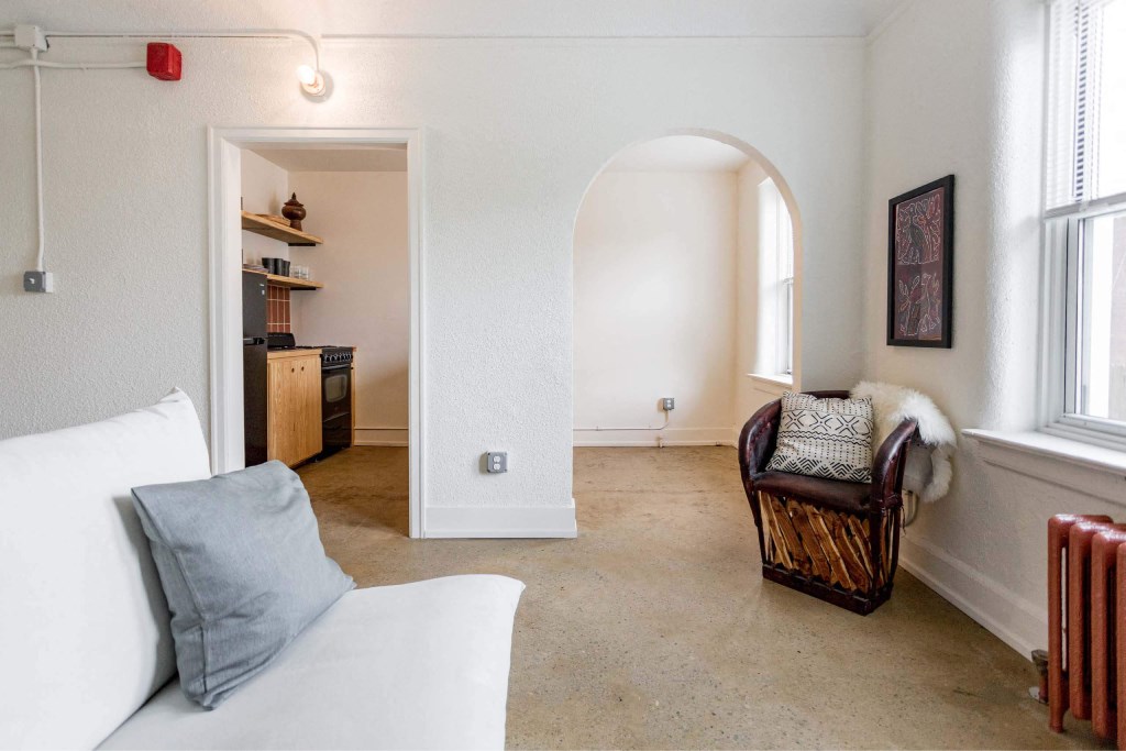 A living room with a white couch and a brown chair.