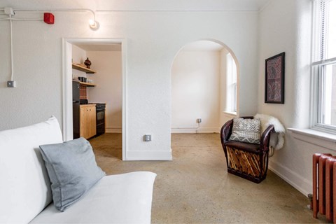 A living room with a white couch and a brown chair.