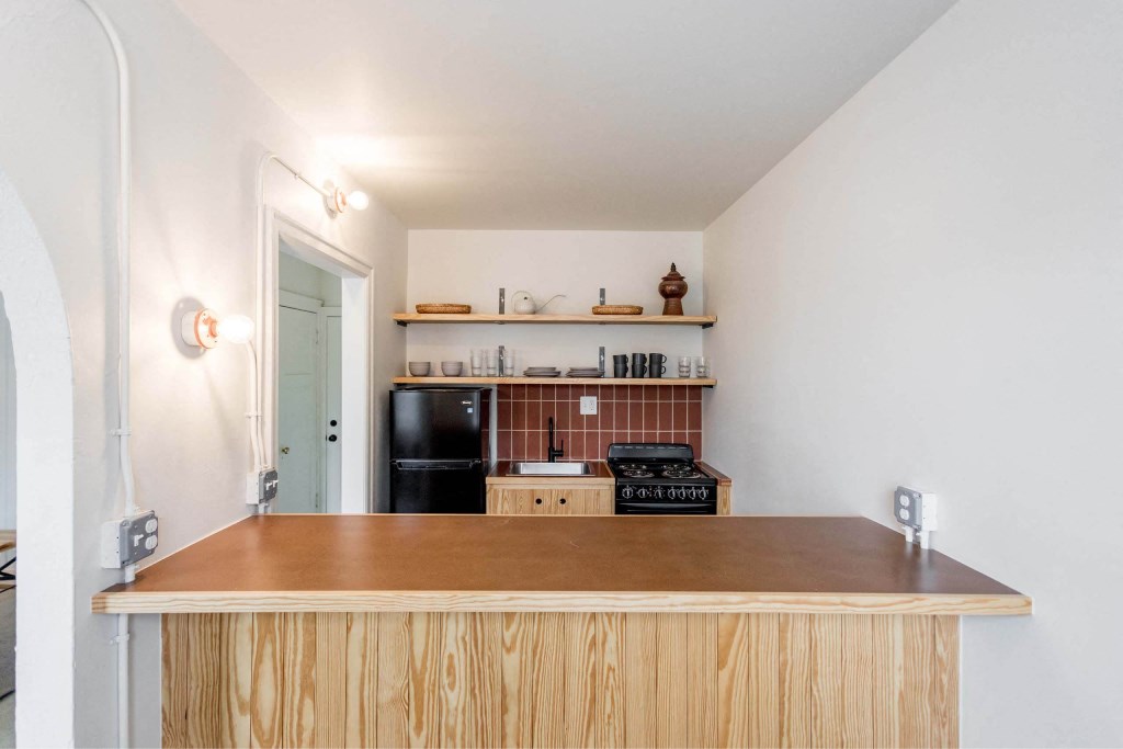 A kitchen with a wooden counter and a black fridge.