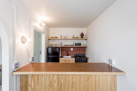A kitchen with a wooden counter and a black fridge.
