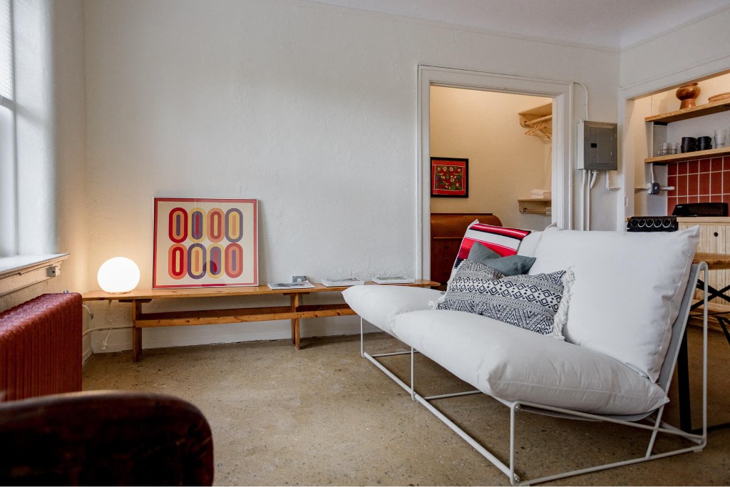 A living room with a white couch and a red chair.