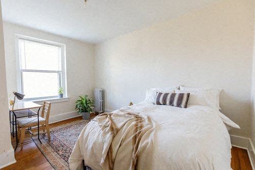 A bedroom with a bed, chair, and window.