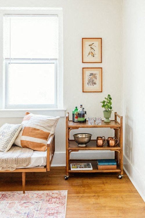 A wooden chair with a cushion and a pillow is in front of a window.