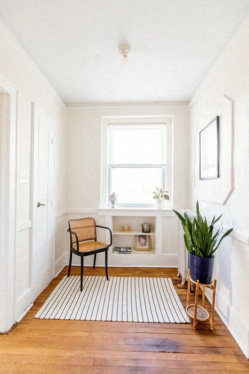 A room with a chair, a potted plant, and a window.