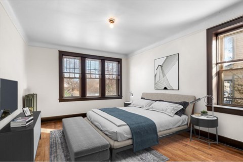 A bedroom with a bed, a nightstand, and a window.