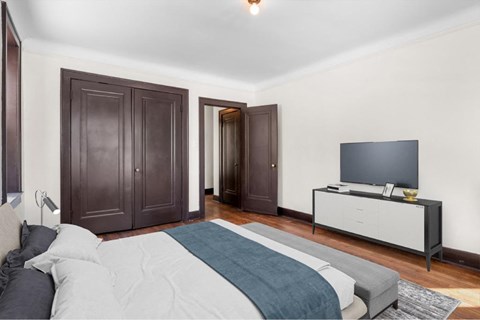 A bedroom with a bed, a dresser, and a television.