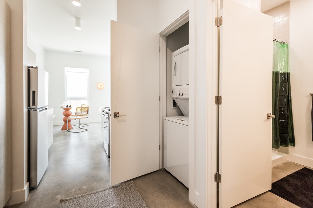 A kitchen with a refrigerator, a dining table with chairs, and a washing machine.