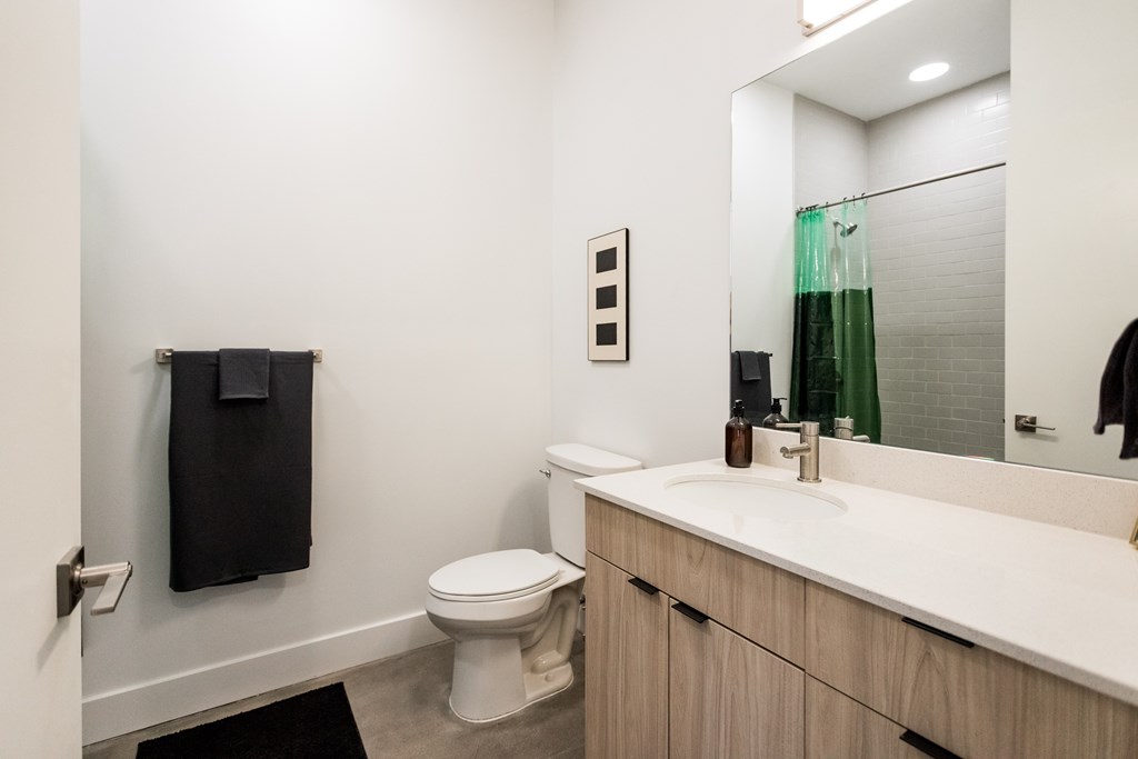 A bathroom with a toilet, sink, and mirror.