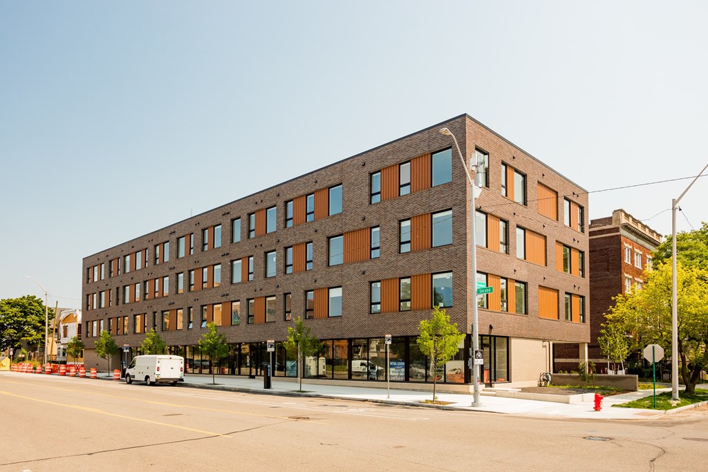 A large building with a brown and orange facade sits on a street corner.