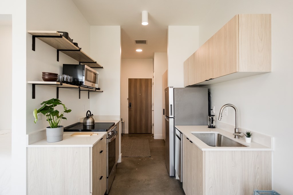 A modern kitchen with a refrigerator, sink, and oven.