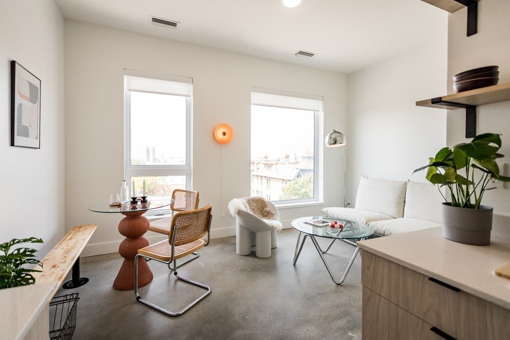 A living room with a white couch, a wooden table, and a chair.