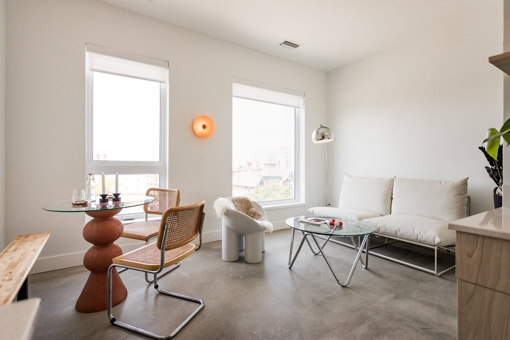 A living room with a white couch, a wooden table, and a chair.