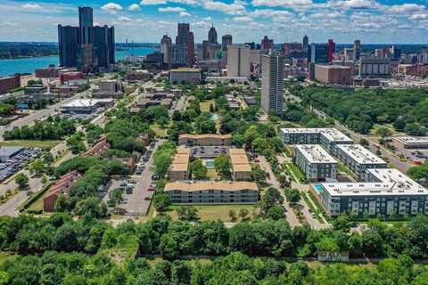 A cityscape with a mix of residential and commercial buildings, surrounded by lush greenery.