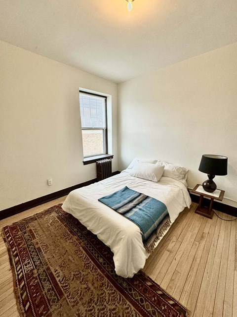A bedroom with a bed, a lamp, and a rug.