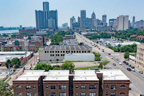 A cityscape with a mix of modern and older buildings, a busy street with cars, and a body of water in the distance.