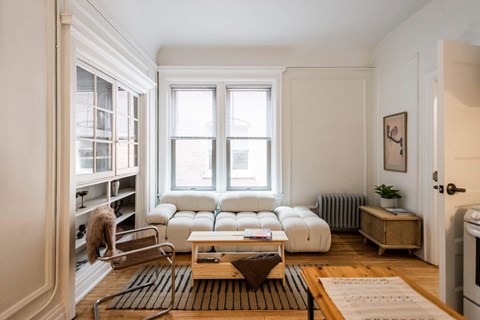 A living room with a white sofa set and a wooden coffee table.
